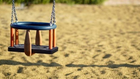 Kleinkindschaukel mit Sand und Hecke